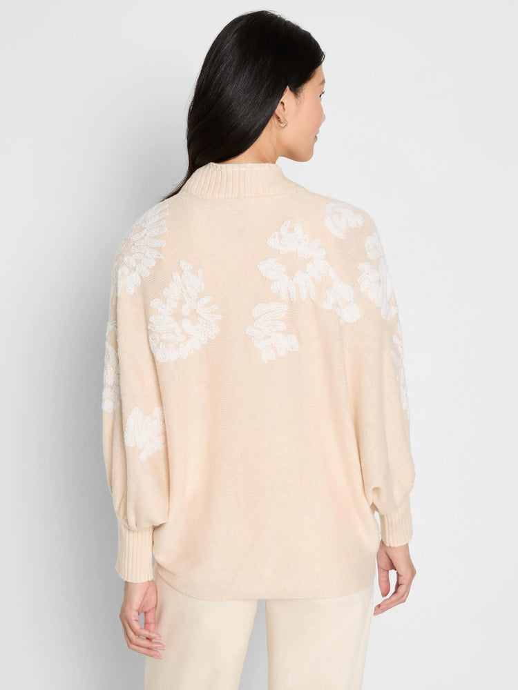 Light beige cardigan with white embroidered floral patterns on back and sleeves. Ribbed mock neck and cuffs.