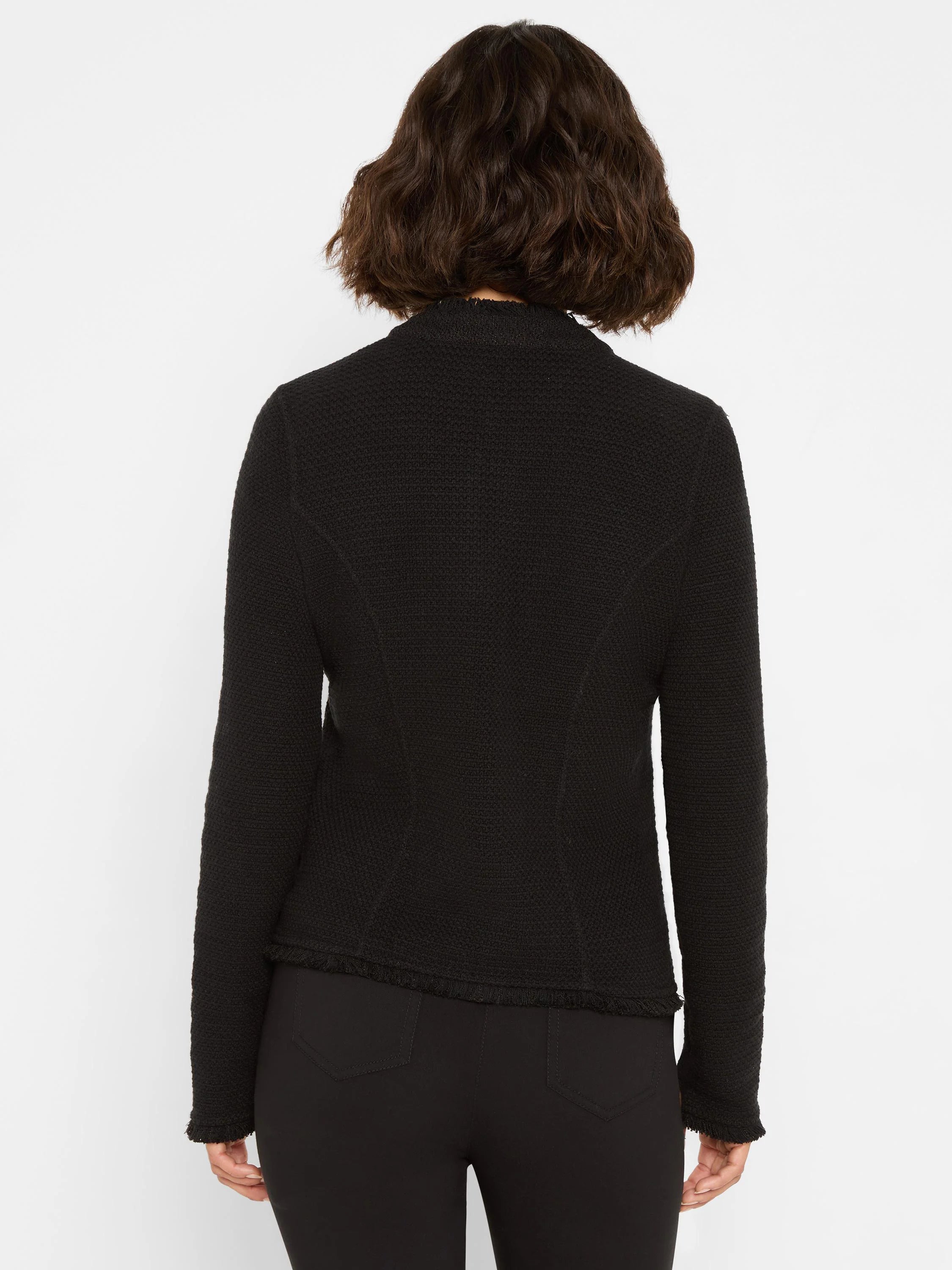 Black textured knit jacket with a stand-up collar, fringe at the hem and cuffs. Model viewed from behind.