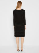 Black long-sleeved dress with ribbed knit top. Skirt features horizontal tiers of soft, fuzzy texture. Fuzzy trim on...