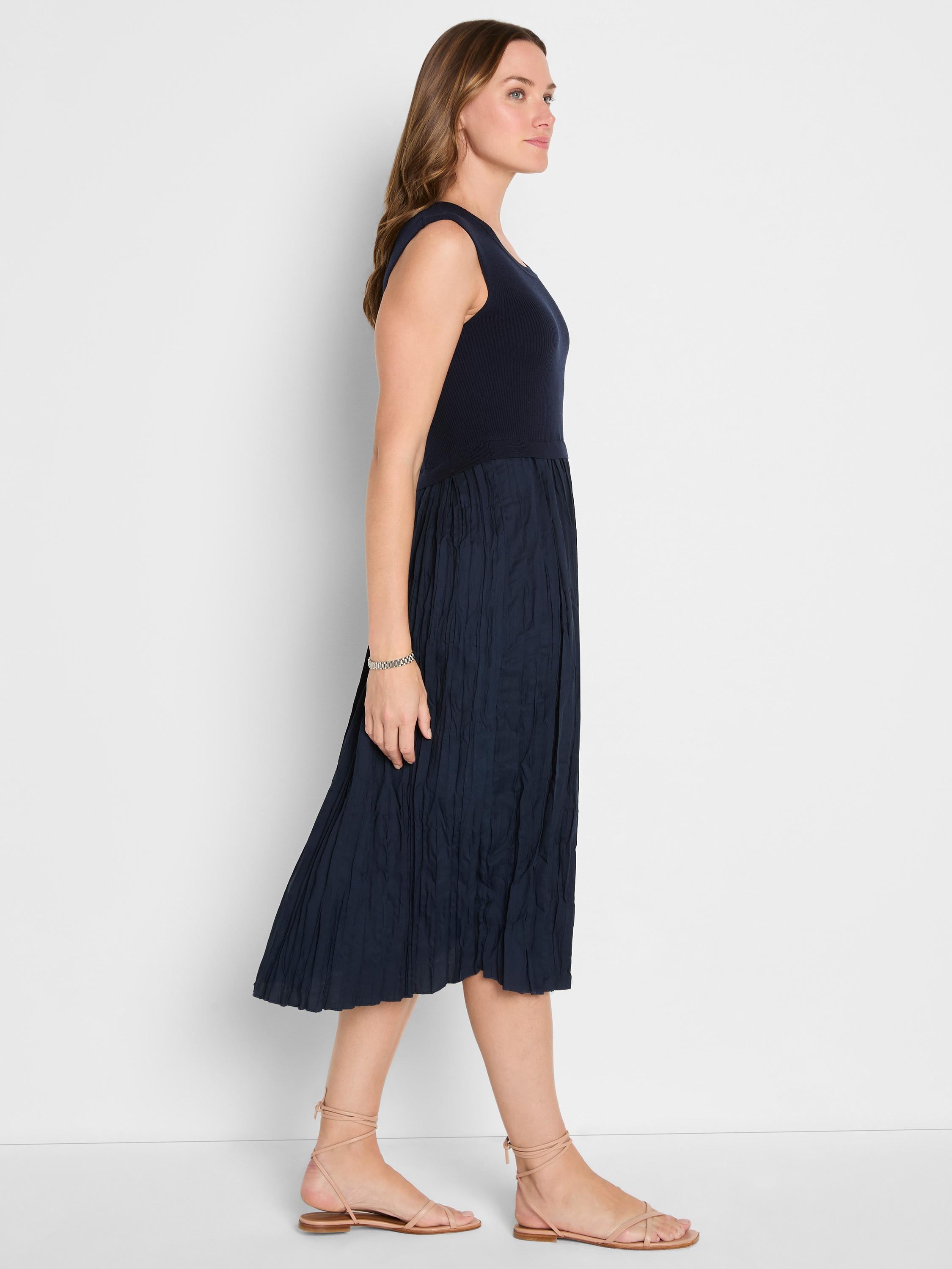 The model wears a navy sleeveless midi dress with a fitted ribbed top and a flowing textured skirt.