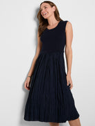A navy sleeveless dress featuring a fitted ribbed knit bodice flows into a textured crinkled midi skirt.