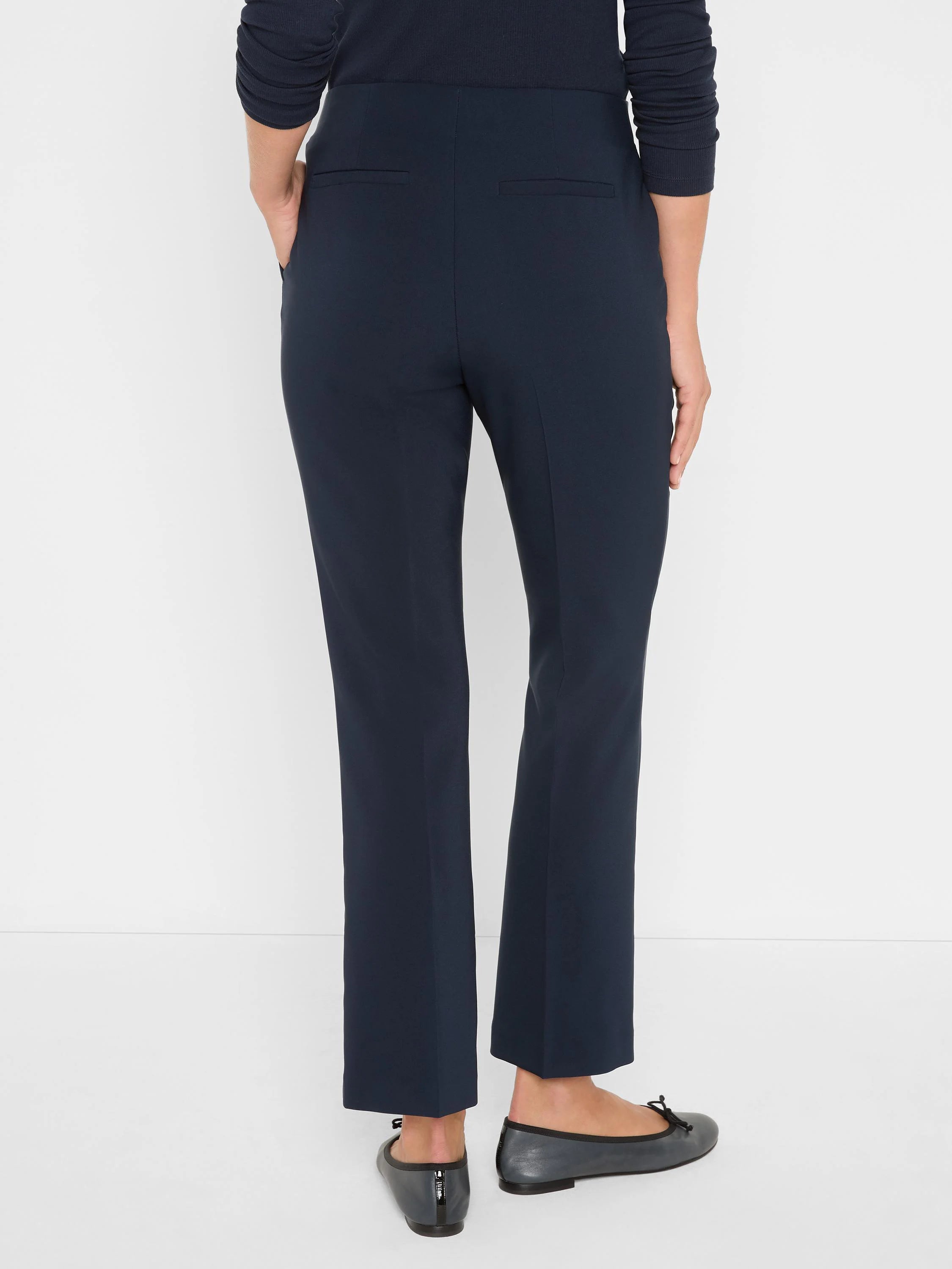 Dark navy blue pants, back view, ankle-length with a subtle demi-boot flare and two back welt pockets.