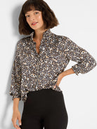 Leopard print top with cream, tan, and dark brown spots. Features a ruffled stand-up collar and 3/4 smocked sleeves.