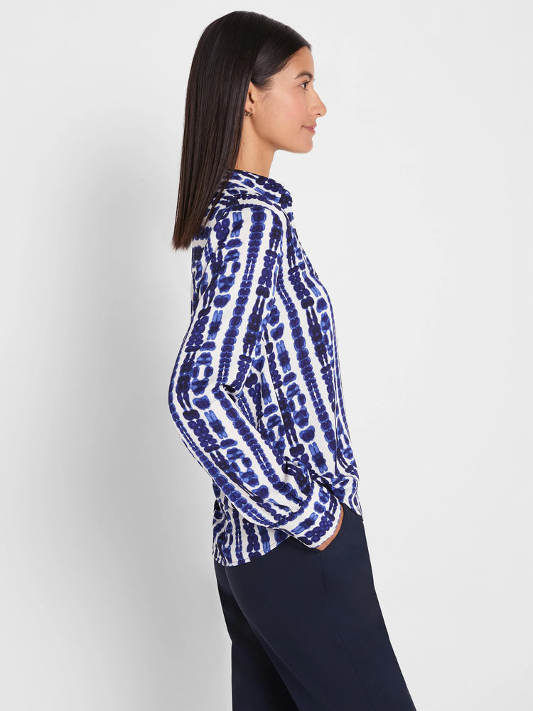 Collared, long-sleeved white top featuring dark blue irregular vertical shibori stripes.