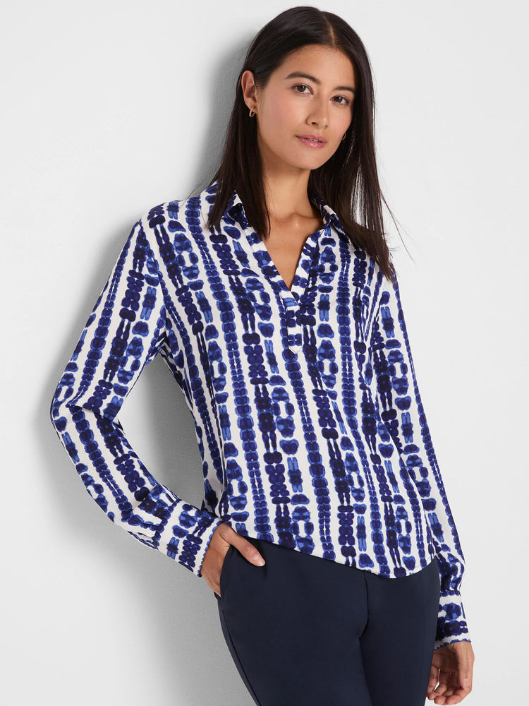 White top with blue shibori vertical stripes; patterns feature irregular, ink-blot shapes. V-neck & collar.