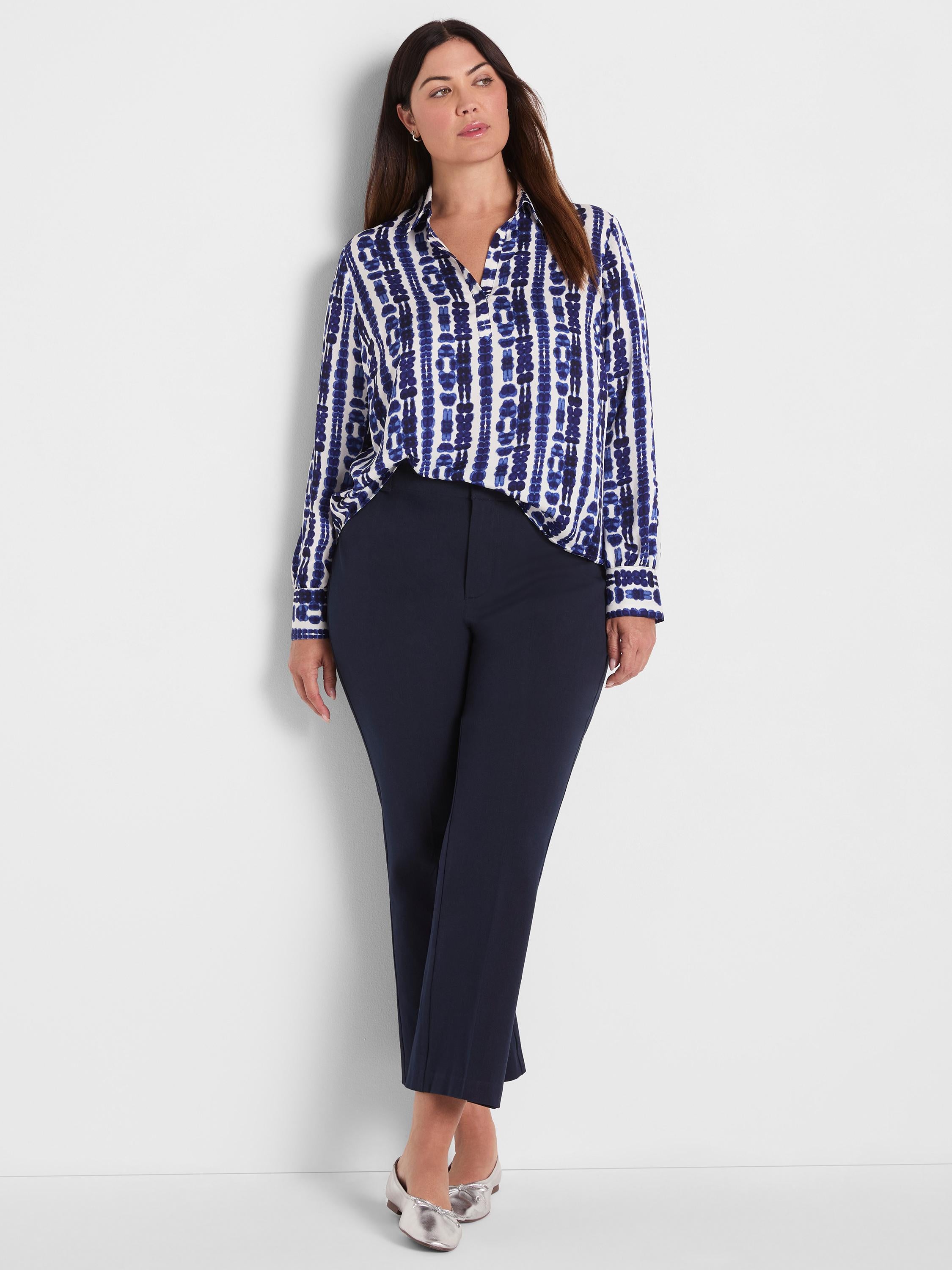 A model wears a relaxed fit blue and white patterned button-up blouse with slim, cropped navy trousers.
