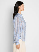 Light blue cotton shirt with long sleeves & painted vertical stripes: blues, browns, & tan.