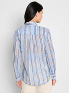 Light blue shirt with uneven vertical stripes in shades of blue, brown, and beige, worn from the back.