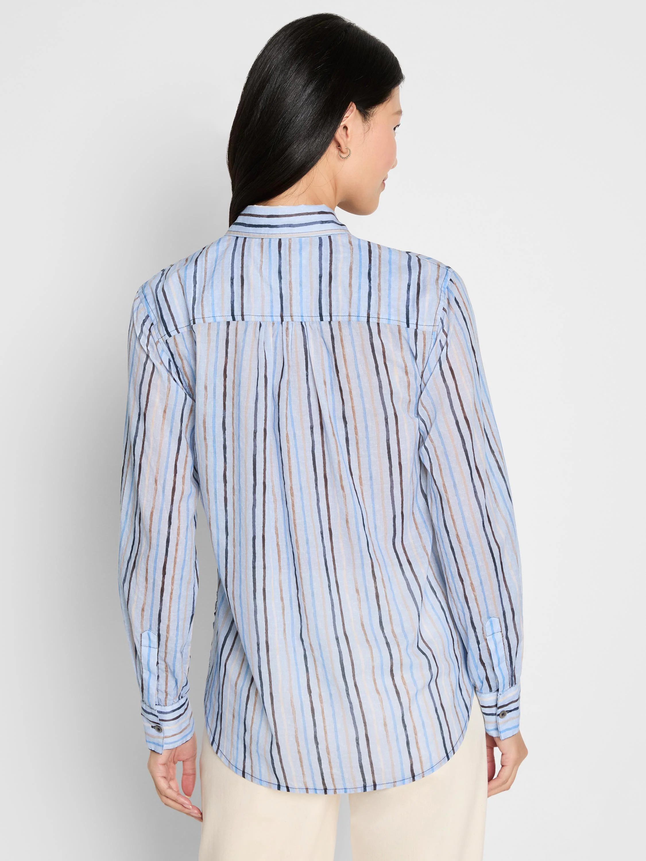 Light blue shirt with uneven vertical stripes in shades of blue, brown, and beige, worn from the back.