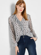 Light grey blouse with dark grey square pattern, V-neck ruffle, and long sleeves.