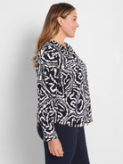 Indigo top with white abstract wavy pattern, long-sleeved and collared. Worn by a woman in profile.