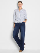 Model wears a fitted blue and white striped tie-front blouse and dark wash high-rise wide-leg denim pants.