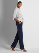 A fitted striped wrap blouse is styled with relaxed, high-waisted dark denim wide-leg trousers.