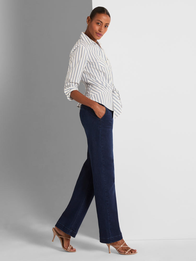 A fitted striped wrap blouse is styled with relaxed, high-waisted dark denim wide-leg trousers.