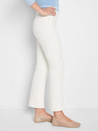 White bootcut jeans on a model, side view. High waist, slim through the thigh, with a gentle flare at the hem.