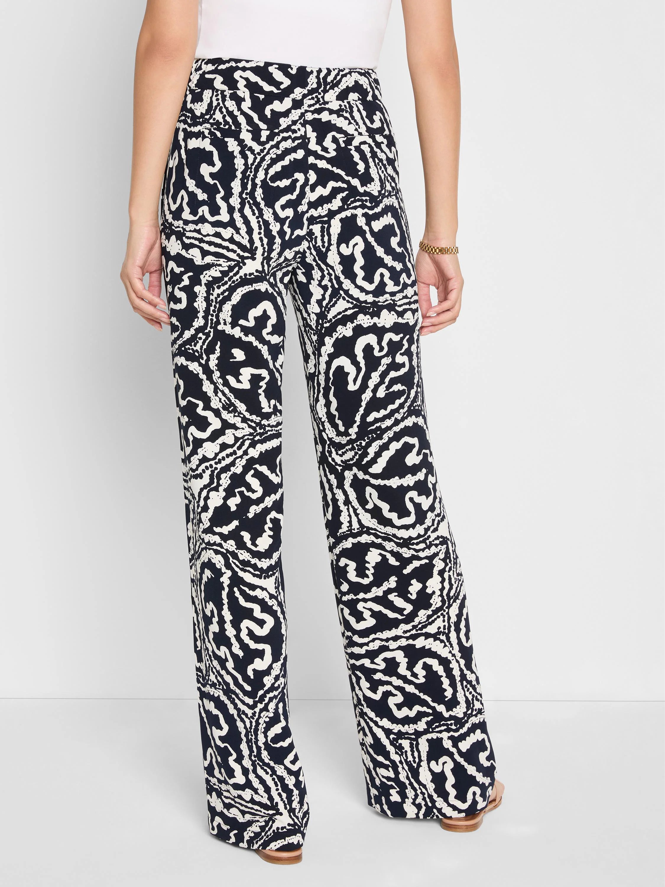 Indigo wide-leg pants with a high-contrast swirling white leaf pattern. Shown worn from behind.
