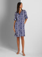 A relaxed blue and white tie-dye stripe shirtdress with short sleeves and pockets is worn above the knee.