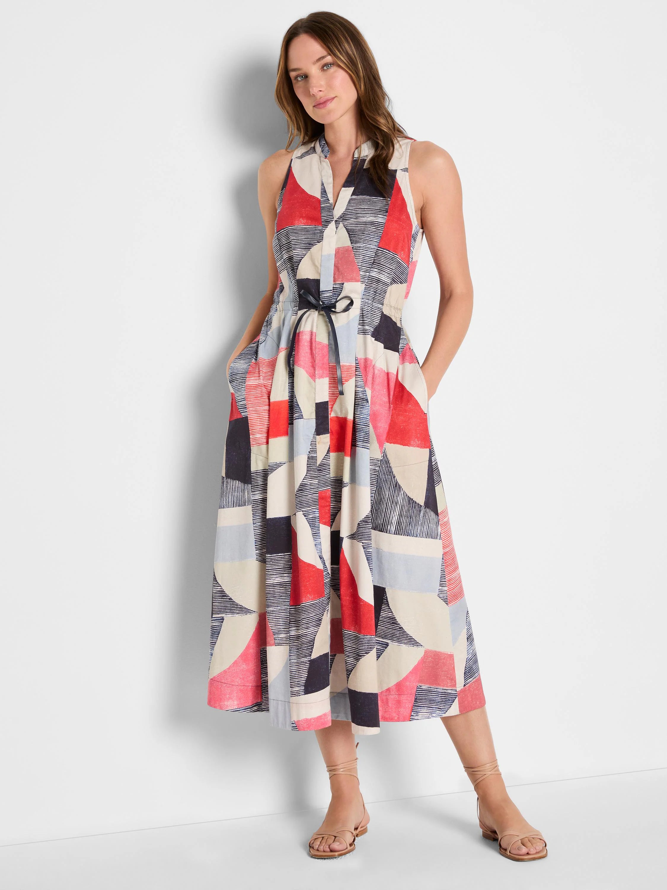 Sleeveless V-neck midi dress in red, navy, light blue, and cream geometric print with a tied waist. Pockets.