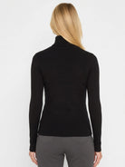 Black rib knit turtleneck, worn from behind. Features a folded collar, long sleeves, and visible ribbed texture.