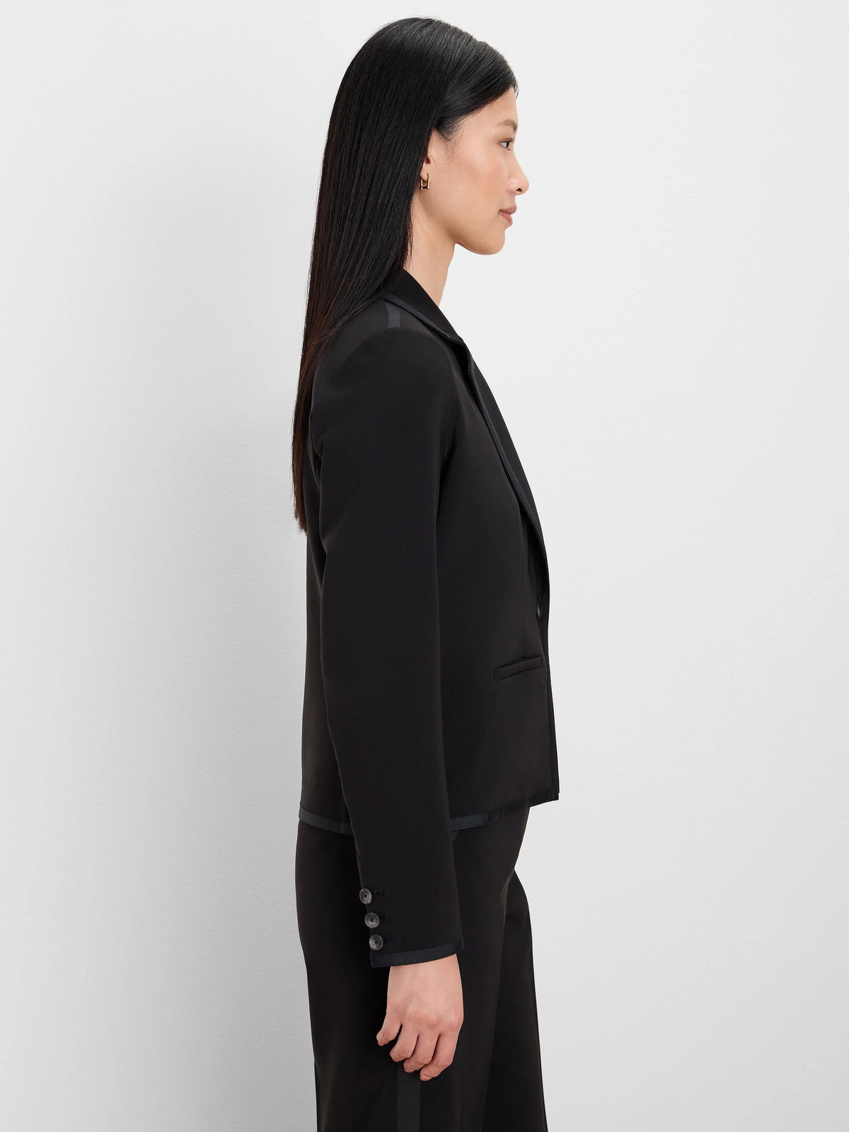 Black blazer with grosgrain ribbon trim on lapels, shoulder tabs, and cuffs. Three dark cuff buttons are visible.