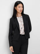 Black cropped pinstripe blazer with thin white stripes and notched lapels.