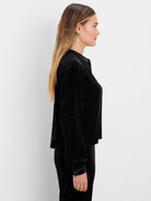 Black velvet top, model side profile. Features a band collar, puffed long sleeves with button cuffs.