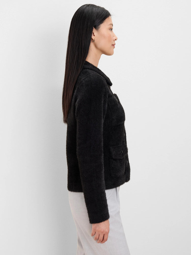 Black fuzzy jacket with patch pockets, dark buttons, and a collar. Side profile view.