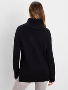 Black foldover turtleneck sweater, back view. Features ribbed cuffs, hem, and a silver side zipper.