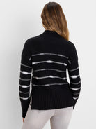 Black sweater with horizontal white textured stripes on body and sleeves. Features a mock neck and ribbed hem with side...
