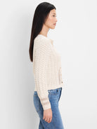 Cream filigree knit cardigan with light buttons, featuring an open pattern and ribbed cuffs.