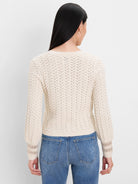 Ecru knit cardigan, back view. Features all-over filigree open-knit pattern & decorative cuffs.