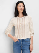 Ivory button-front cardigan with intricate openwork knit panels and a round neck. Features light-colored buttons.