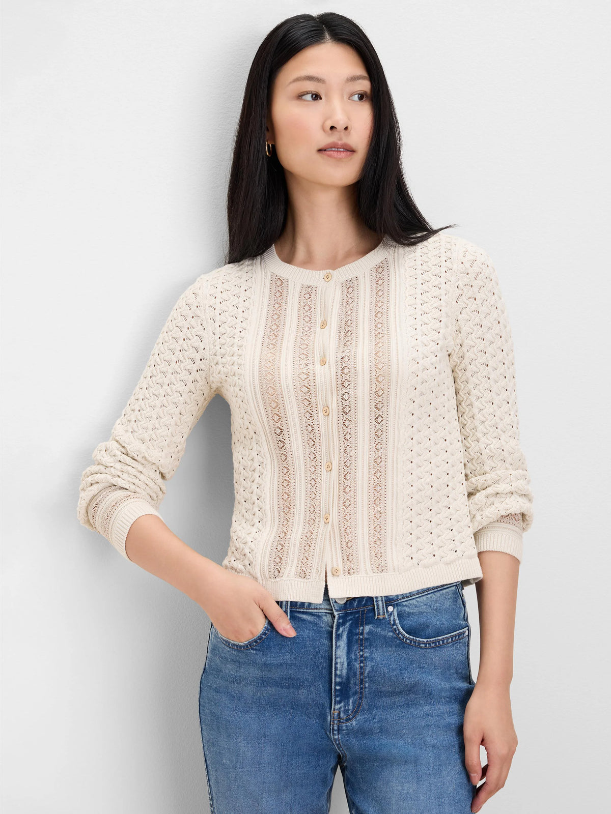 Ivory button-front cardigan with intricate openwork knit panels and a round neck. Features light-colored buttons.