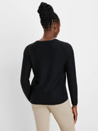 Black knit sweater with shimmering flecks, long raglan sleeves, ribbed cuffs and hem. Back view.