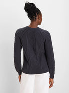 Dark gray sweater with intricate, varied cable knit patterns on the back and sleeves; ribbed cuffs and hem.