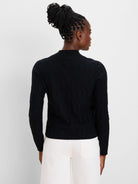Black mockneck cardigan, back view. Detailed with an all-over diamond cable knit pattern.