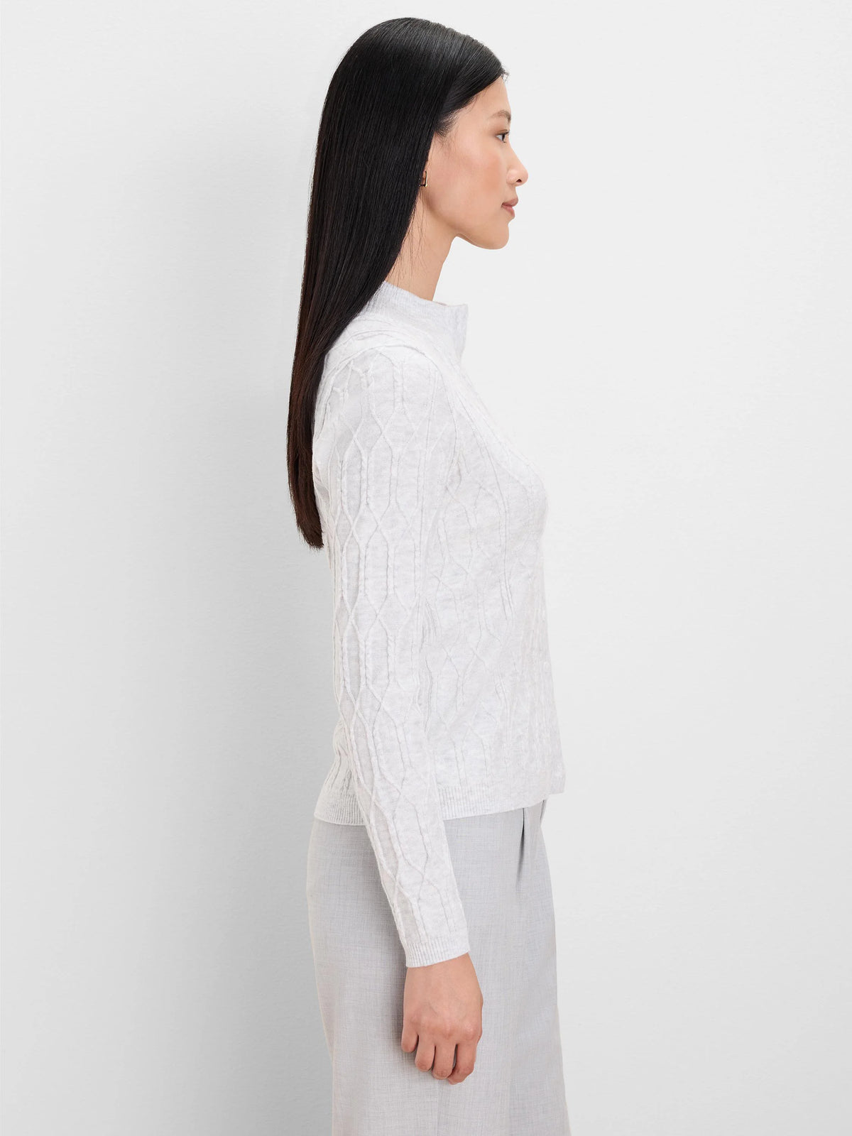 Light gray cable knit mockneck cardigan, worn by a model in side profile.