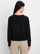 Black, soft-textured sweater with long raglan sleeves, ribbed cuffs & hem. Model shown from behind.