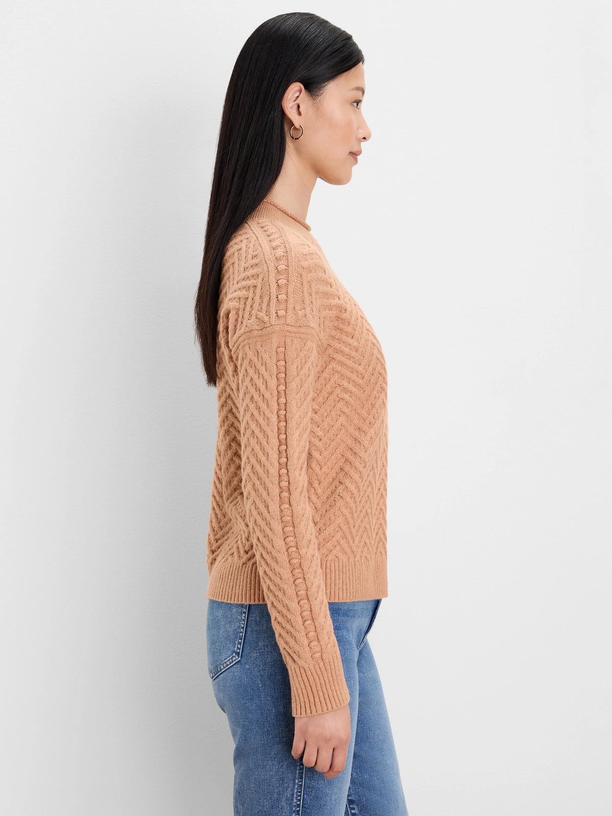 Peach-beige roll neck sweater with a chevron knit pattern, vertical bobbles on the shoulder, and ribbed cuffs.