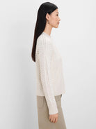 Cream roll neck sweater with cable knit sleeves featuring bobbles, and a chevron pattern on the body.