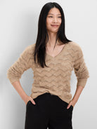 Beige V-neck sweater with fuzzy texture, gold shimmer, and scallop knit pattern.