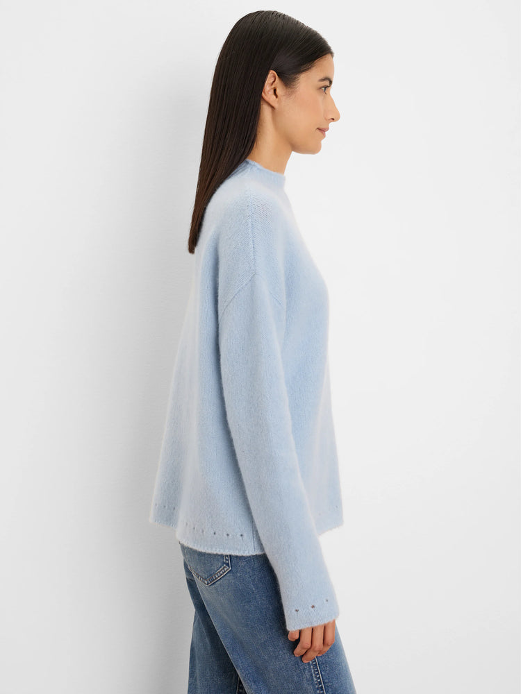 Light blue fuzzy sweater with relaxed fit, high neck, and small eyelets on hem and cuffs.
