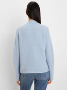 Pale blue fuzzy knit sweater with a mock neck and small dark perforations along the bottom hem and sleeves.