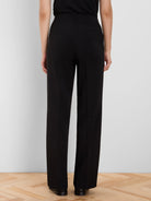Black wide leg high-waisted pants, shown from the back, with two flat welt pockets.