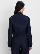 Dark indigo denim jacket, back view. Features a band collar and long sleeves with gathered elastic cuffs.