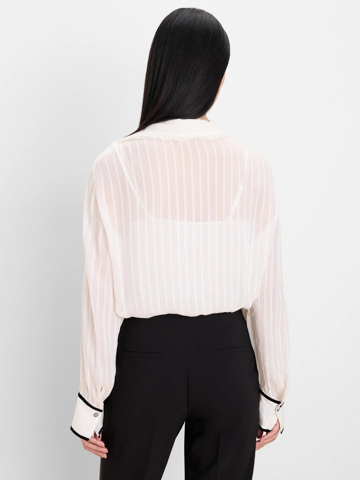 Cream semi-sheer vertically striped shirt with black velvet cuff trim. Back view.