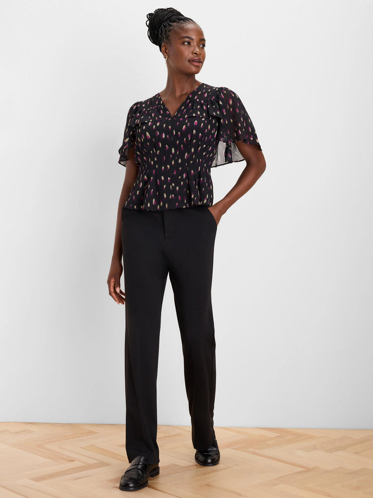 Black V-neck flutter top with sheer sleeves and peplum waist. Patterned with magenta and gold elongated dots.