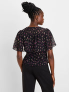 Black top with magenta & gold abstract strokes, flutter sleeves, and a cinched waist.
