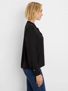 Black long-sleeve shirt with ruffled front, stand collar, and white buttons on cuffed wrists.