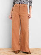 Rust wide leg jeans with a double button high waist and prominent vertical front seams.